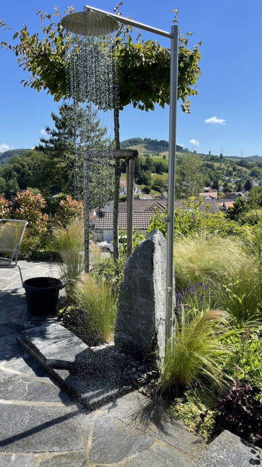 Gartendusche im Steingarten zwischen Gräsern
