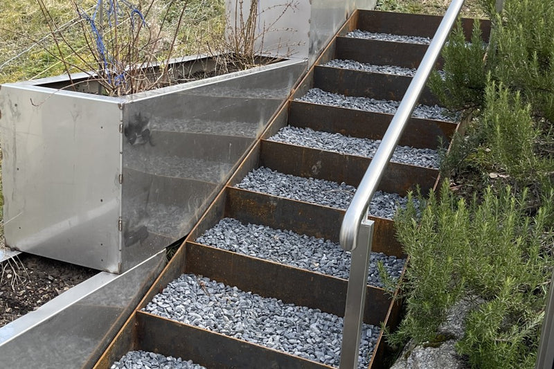 Edelstahl-Handlauf, angeschweisst an eine Naturtreppe aus Cortenstahl
