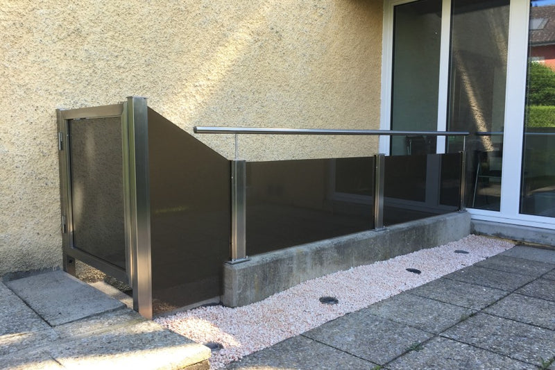 Einfassung einer Kellertreppe mit braun getöntem VSG-Milchglas und abschliessbarer Gartentüre