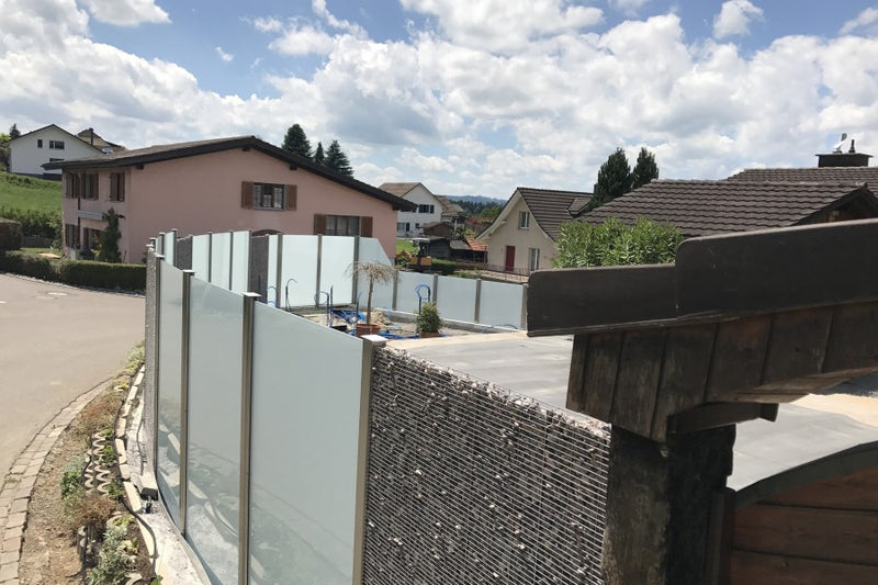 Sicht-, Wind- und Schallschutz aus Gabionen und VSG-Milchglas – Bettwiesen