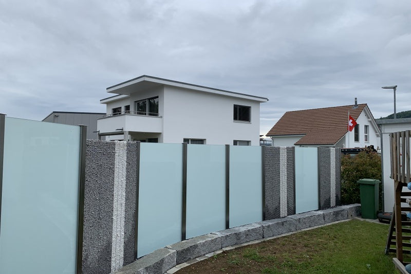 Sicht-, Wind- und Schallschutz aus Steinkörben und VSG-Milchglas – Kaisten AG