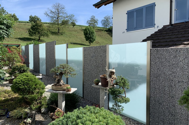 Sicht- und Windschutz aus Steinkörben und VSG-Milchglas – Wallbach AG