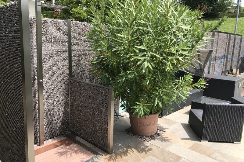 Sicht-, Wind- und Schallschutz aus Gabionen und VSG-Milchglas mit integrierter Gartendusche – Bettwiesen