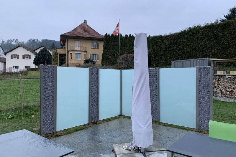 Sicht-, Wind- und Schallschutz aus Steinkörben und VSG-Milchglas – Oberhofen AG