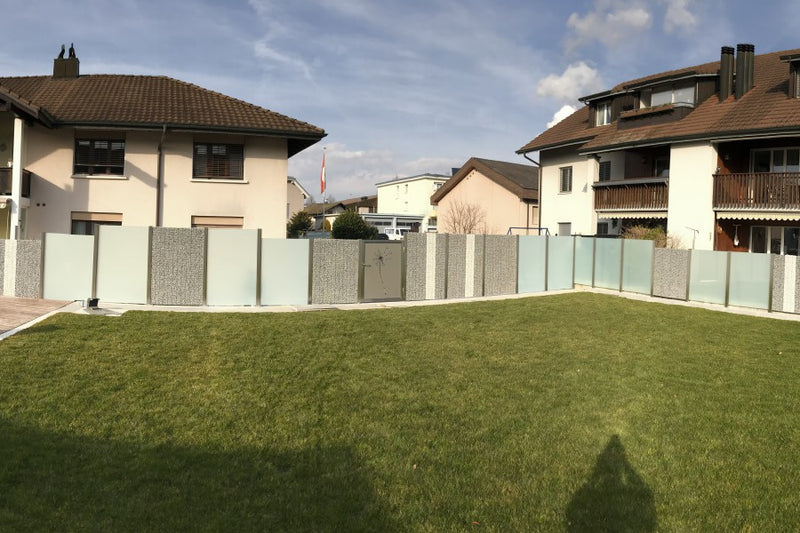 Sicht- und Windschutz aus Steinkörben und VSG-Milchglas – Leibstadt AG