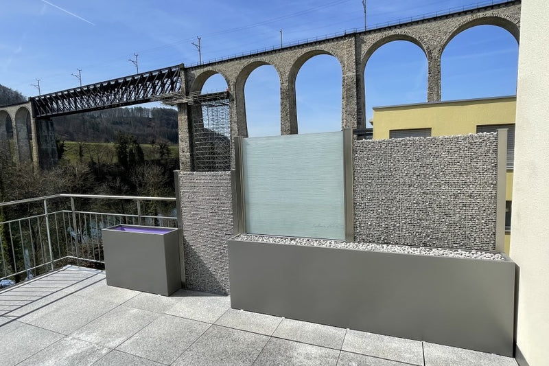 Sicht- und Windschutz aus VSG-Milchglas und Steinkörben, montiert auf einem Hochbeet – Eglisau ZH