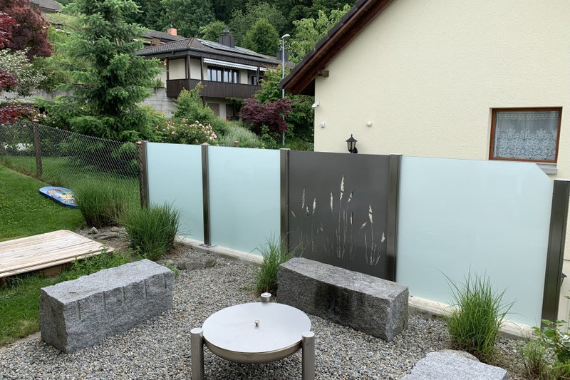 Sicht- und Windschutz aus VSG-Milchglas und Aluminiumblech mit gelasertem Sujet – Fislisbach AG