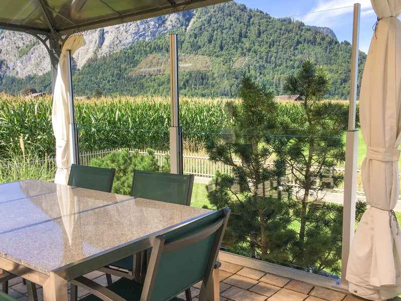 Sitzplatz mit SlideGlass® Windschutz vor Feldern und Bergen